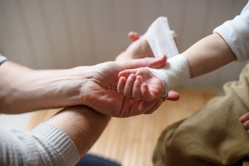 Padre vendando a un pequeño niño herido en casa. foto de archivo libre de regalías