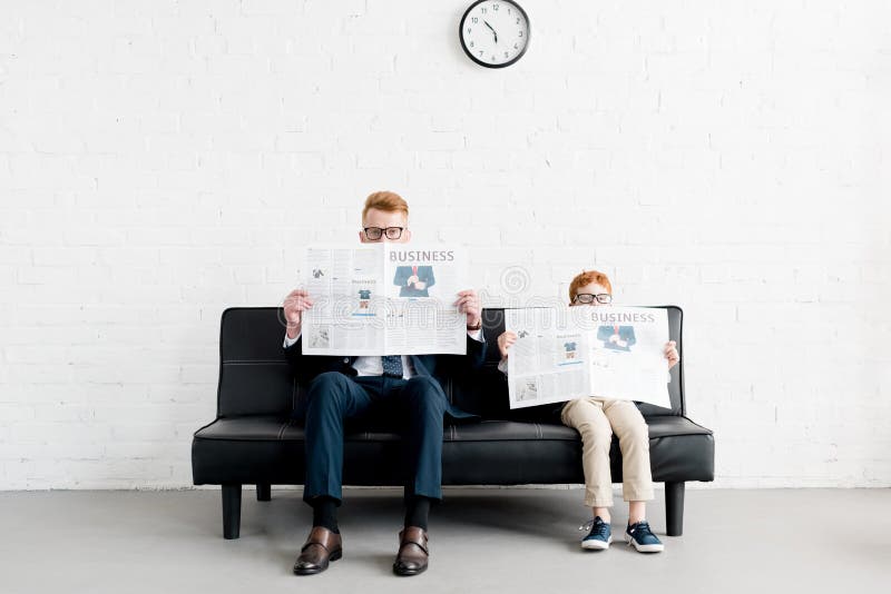 Padre y pequeños hombres de negocios del hijo que llevan las lentes y la lectura fotografía de archivo libre de regalías