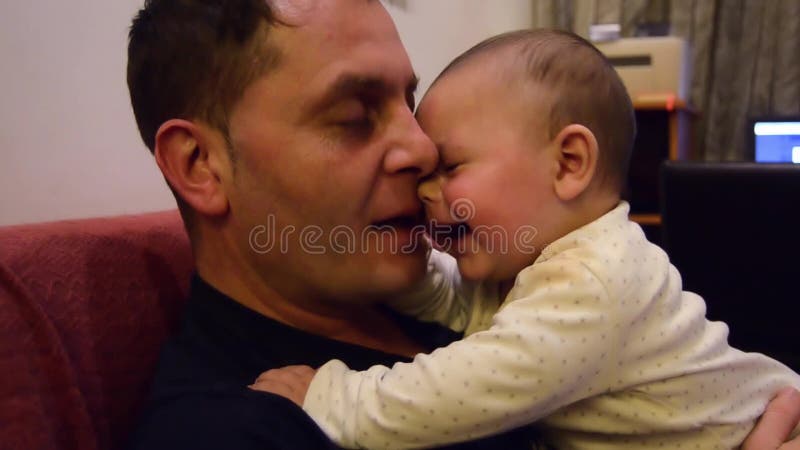 Padre y sus seis meses lindos del bebé que abraza y que habla, pasando una cierta hora de la calidad junta