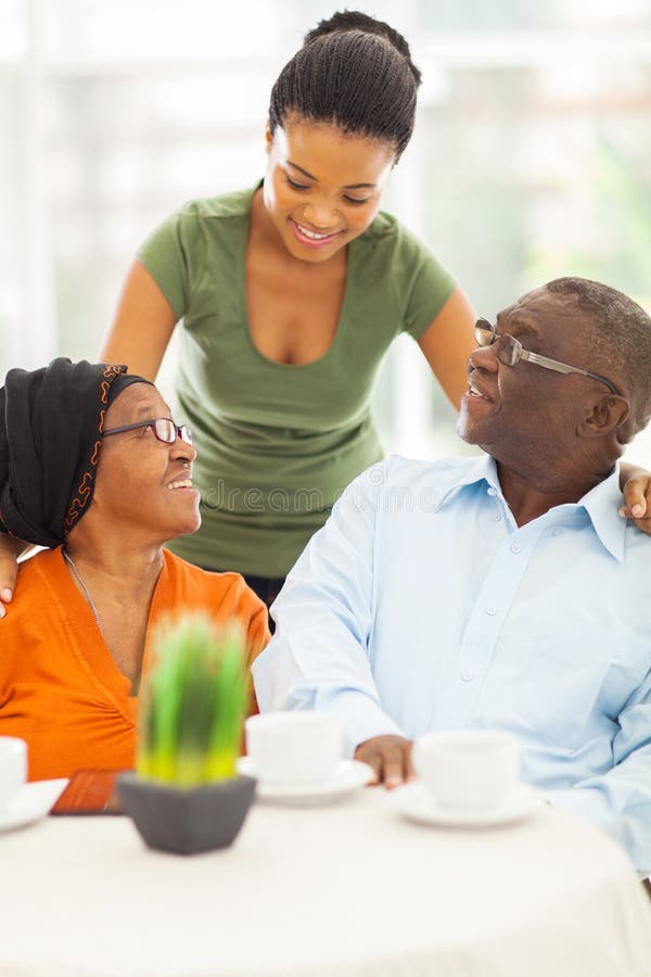 Beautiful african girl talking to senior parents at home. Beautiful african girl talking to senior parents at home