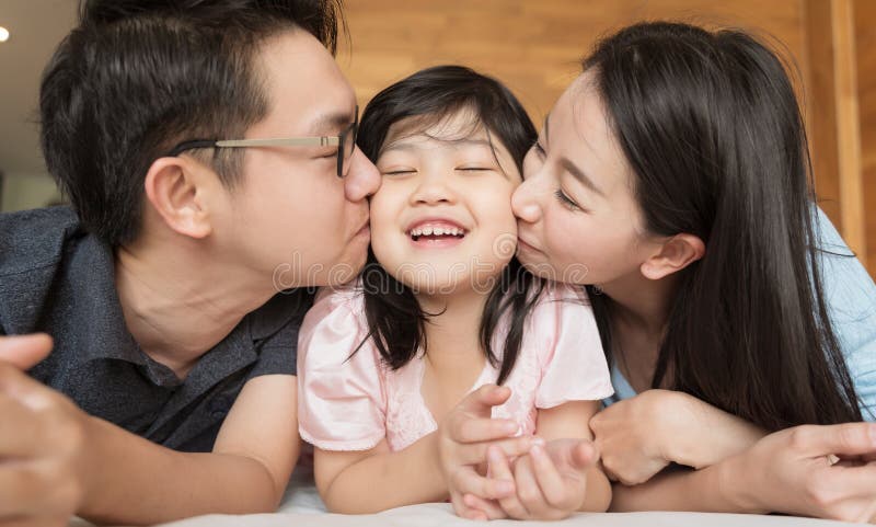 Asian Parents kissing their little daughter on both cheeks. family portrait. Asian Parents kissing their little daughter on both cheeks. family portrait