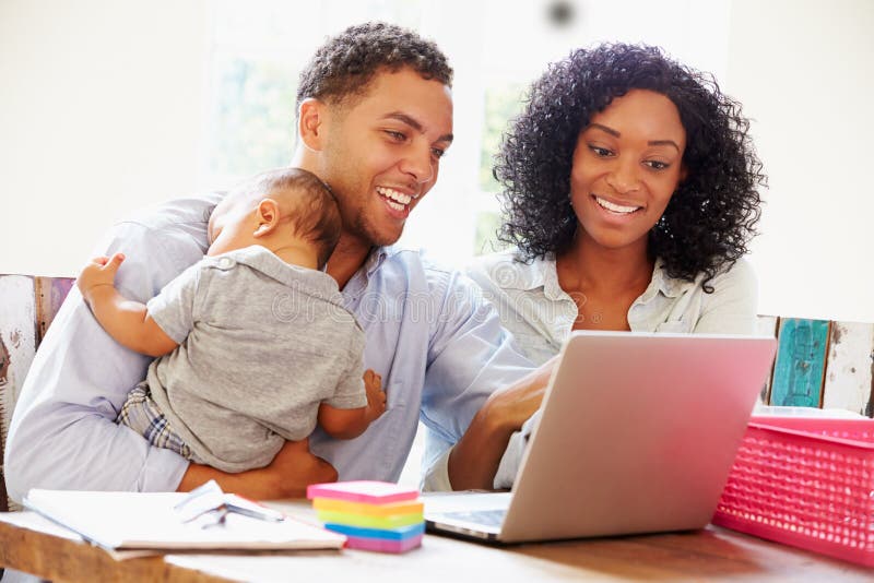 Padres con el bebé que trabaja en oficina en casa imagenes de archivo