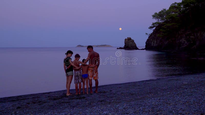 Padres con niños en el mar por la noche almacen de metraje de vídeo