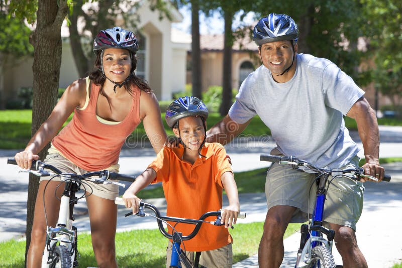 Padres del afroamericano con la bici del montar a caballo del hijo del muchacho imagen de archivo Padres del afroamericano con la bici del montar a caballo del hijo del muchacho imagen de archivo