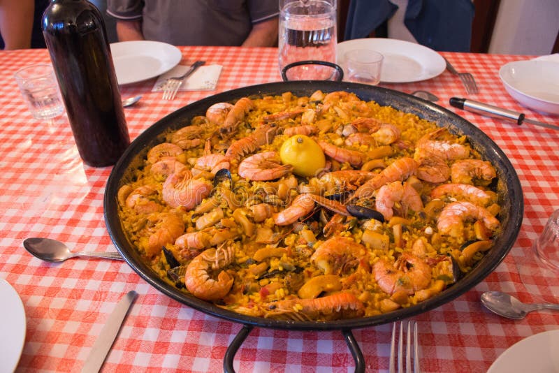 Paella de marisco en manteles de cuadros Delicioso marisco Cocina mediterránea Pan de paella con gambas y botella de vino fotografía de archivo libre de regalías Paella de marisco en manteles de cuadros Delicioso marisco Cocina mediterránea Pan de paella con gambas y botella de vino fotografía de archivo libre de regalías