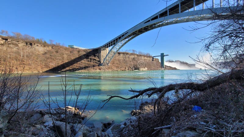 Paesaggio del ponte sull'arco di un fiume sullo sfondo delle cadute del niagara. Un paesaggio del ponte arcato sopra un fiume sullo sfondo del niagara cade