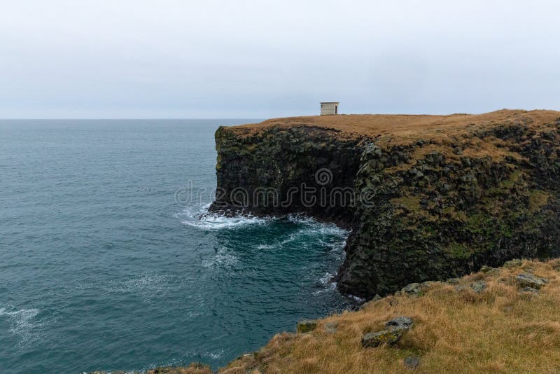 Un paesaggio della costa di arnarstapi circondata dal mare sotto un cielo nuvoloso negli snaefellsnes Islanda