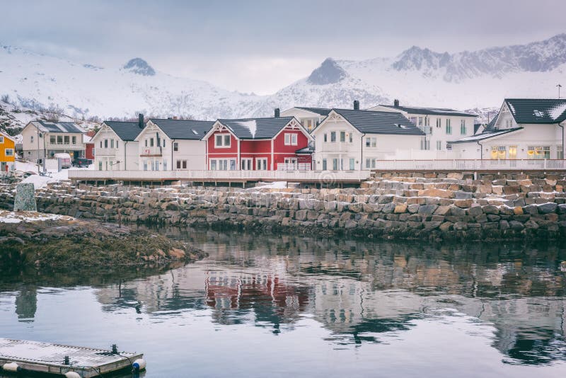 Paesaggio di inverno con le case bianche e rosse, riflessione nell'acqua e picchi di montagna nevosi, Kabelvag, isole di Lofoten, immagine stock Paesaggio di inverno con le case bianche e rosse, riflessione nell'acqua e picchi di montagna nevosi, Kabelvag, isole di Lofoten, immagine stock