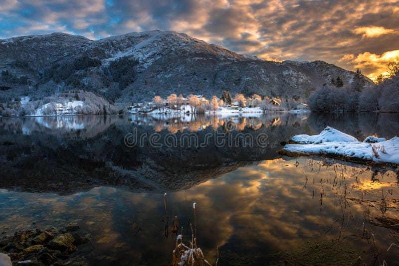 Paesaggio di inverno con le montagne di Snowy, le nuvole variopinte e la riflessione del lago al tramonto immagine stock Paesaggio di inverno con le montagne di Snowy, le nuvole variopinte e la riflessione del lago al tramonto immagine stock