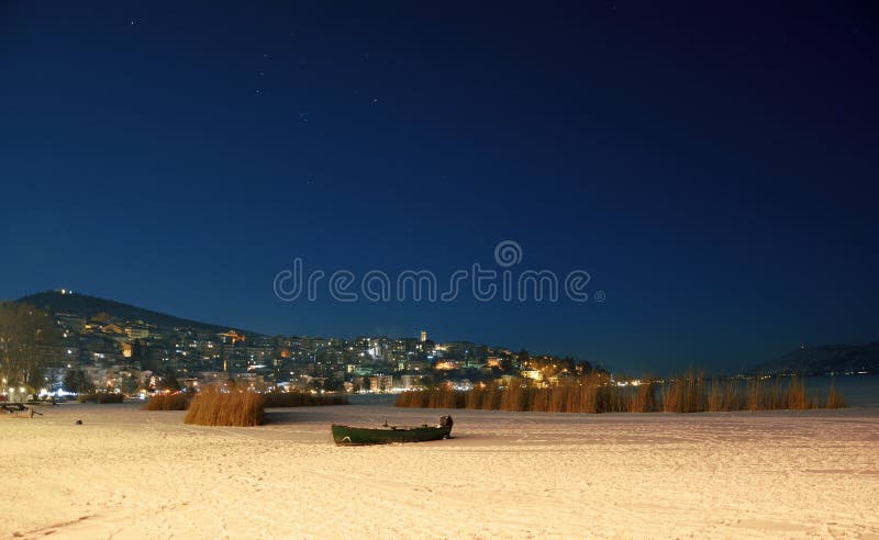 Paesaggio di notte di inverno in città con il lago congelato fotografia stock libera da diritti Paesaggio di notte di inverno in città con il lago congelato fotografia stock libera da diritti