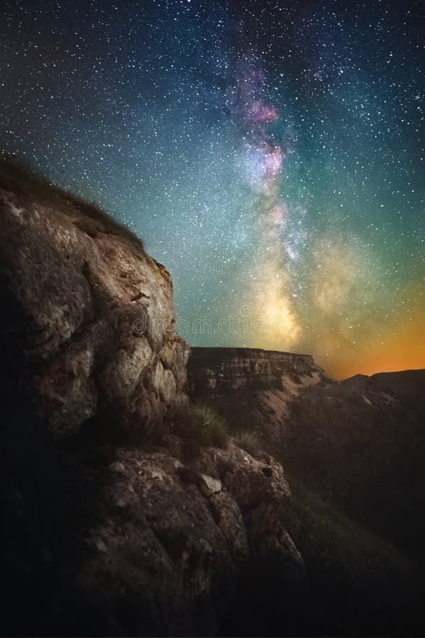 Paesaggio di notte di una scogliera con una gola nei precedenti ed in una Via Lattea verticale Immagine vaga in un modo favoloso immagini stock libere da diritti Paesaggio di notte di una scogliera con una gola nei precedenti ed in una Via Lattea verticale Immagine vaga in un modo favoloso immagini stock libere da diritti