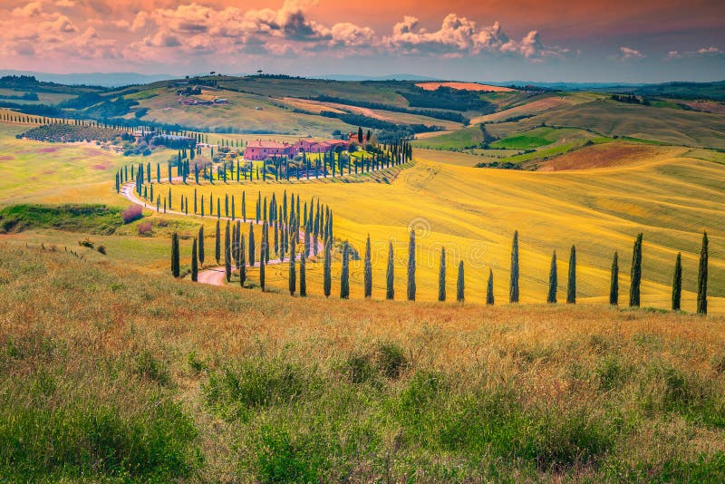Paesaggio idilliaco della Toscana al tramonto con la strada rurale curva, Italia immagine stock libera da diritti Paesaggio idilliaco della Toscana al tramonto con la strada rurale curva, Italia immagine stock libera da diritti