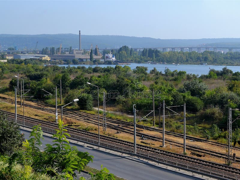Paesaggio il giorno soleggiato di estate: il funzionamento della strada principale lungo il fabbricato ferroviario e industriale, immagini stock libere da diritti Paesaggio il giorno soleggiato di estate: il funzionamento della strada principale lungo il fabbricato ferroviario e industriale, immagini stock libere da diritti
