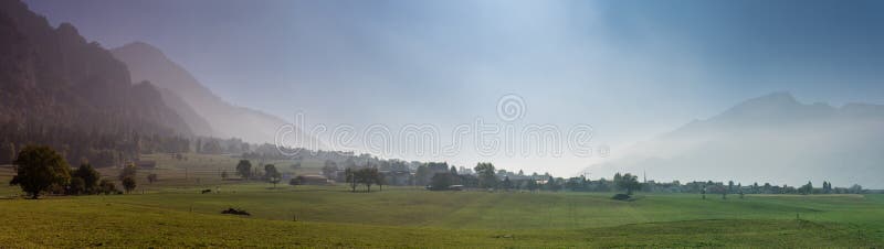 Paesaggio svizzero rurale della campagna con i campi dell'azienda agricola e le montagne nebbiose e foresta in autunno tardo immagine stock libera da diritti Paesaggio svizzero rurale della campagna con i campi dell'azienda agricola e le montagne nebbiose e foresta in autunno tardo immagine stock libera da diritti
