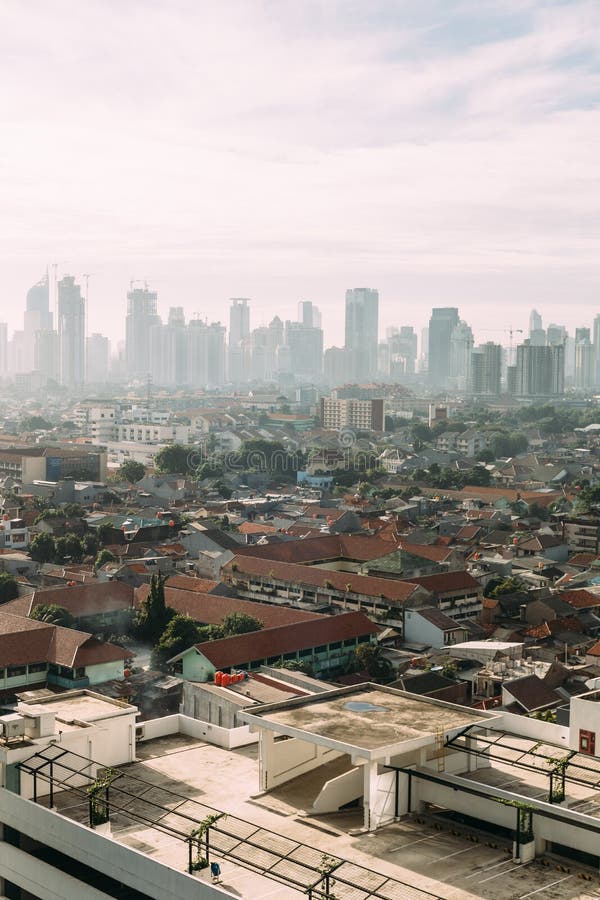 Paesaggio urbano di Jakarta con le alte costruzioni locali di aumento, dei grattacieli e del tetto a spigolo di mattonelle rosse fotografia stock