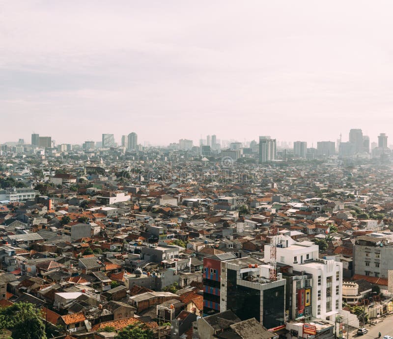 Paesaggio urbano di Jakarta con le alte costruzioni locali di aumento, dei grattacieli e del tetto a spigolo di mattonelle rosse immagine stock