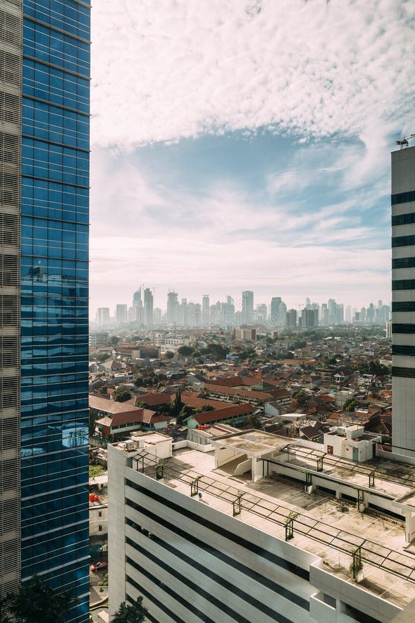 Paesaggio urbano di Jakarta con le alte costruzioni locali di aumento, dei grattacieli e del tetto a spigolo di mattonelle rosse immagini stock