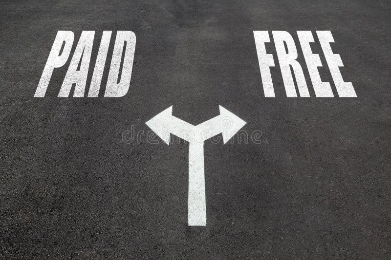 Paid vs free choice concept, two direction arrows on asphalt. Paid vs free choice concept, two direction arrows on asphalt.