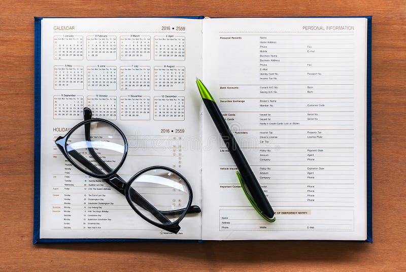 Pagina aperta del calendario del libro del pianificatore del diario con i vetri e penna su Th fotografia stock libera da diritti Pagina aperta del calendario del libro del pianificatore del diario con i vetri e penna su Th fotografia stock libera da diritti