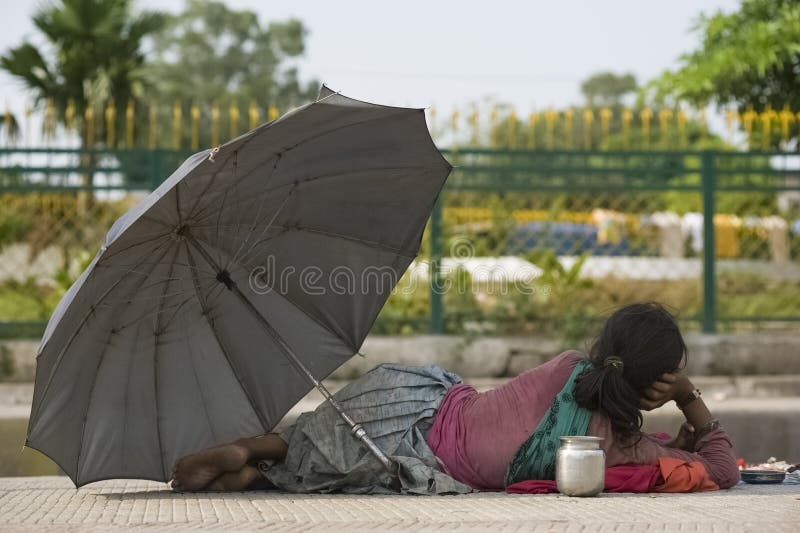 Pahalgam, Jammu and Kashmir, India - August 03, 2011: Homeless Indian woman laying on the streets under an umbrella royalty free stock images Pahalgam, Jammu and Kashmir, India - August 03, 2011: Homeless Indian woman laying on the streets under an umbrella royalty free stock images