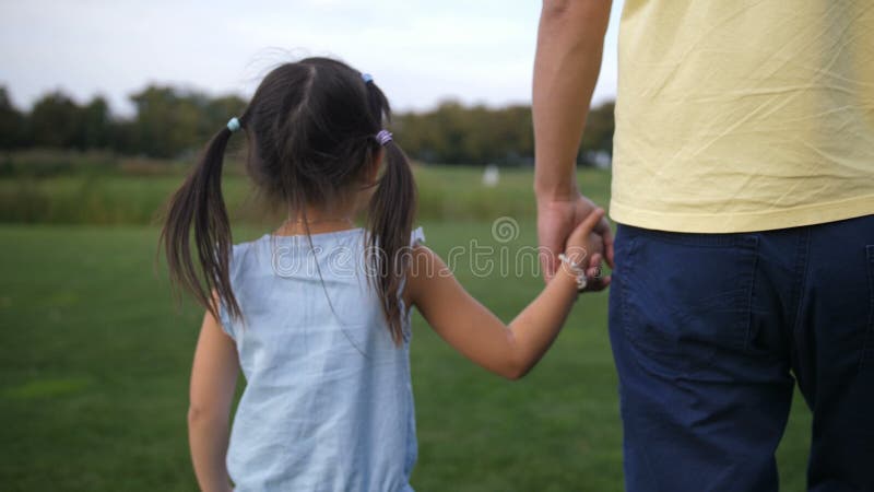 Pai asiático e filha que guardam as mãos e o passeio