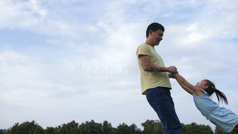 Pai asiático feliz que spiining no círculo sua filha