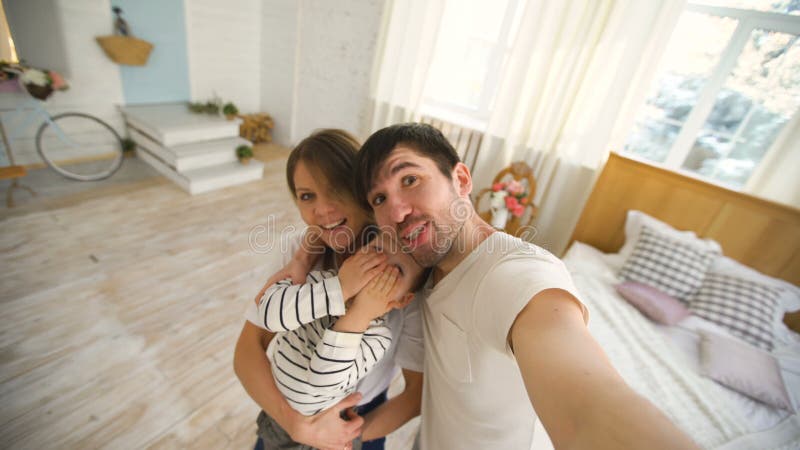 Pai da família feliz que toma o vídeo do selfie na câmera no quarto