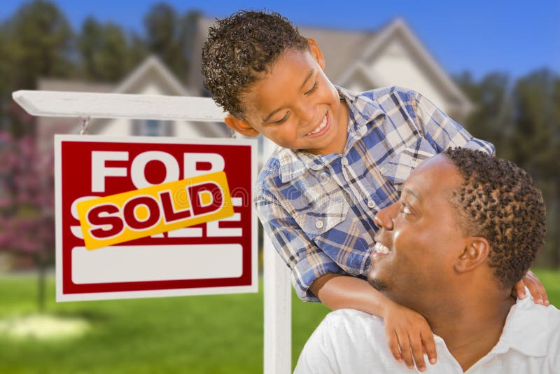 Happy Mixed Race Father and Son In Front of Sold Real Estate Sign and New House. Happy Mixed Race Father and Son In Front of Sold Real Estate Sign and New House.