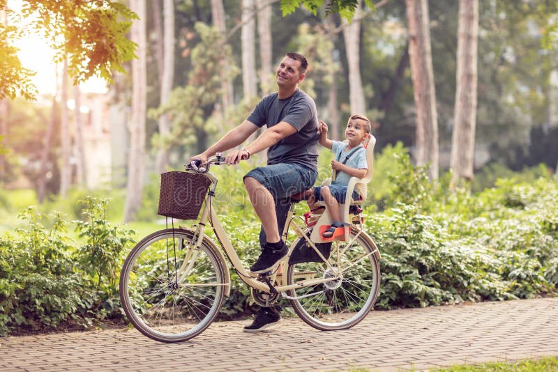 Pai de sorriso com o menino nas bicicletas que têm o divertimento no parque Família s imagem de stock royalty free Pai de sorriso com o menino nas bicicletas que têm o divertimento no parque Família s imagem de stock royalty free