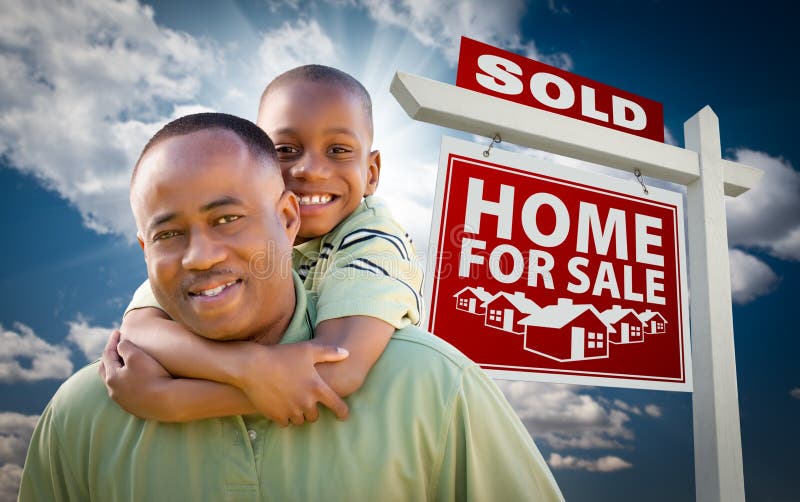 Happy African American Father with Son In Front of Sold Home For Sale Real Estate Sign and Sky. Happy African American Father with Son In Front of Sold Home For Sale Real Estate Sign and Sky.