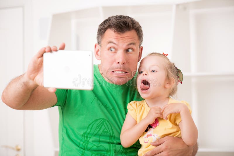 Pai e criança que usa a tabuleta eletrônica em casa fotografia de stock Pai e criança que usa a tabuleta eletrônica em casa fotografia de stock