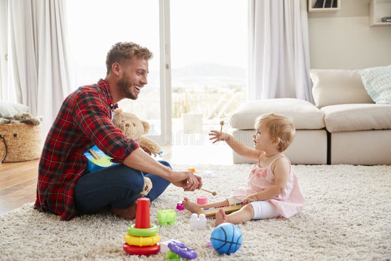 Pai e filha nova que jogam instrumentos do brinquedo em casa imagem de stock Pai e filha nova que jogam instrumentos do brinquedo em casa imagem de stock
