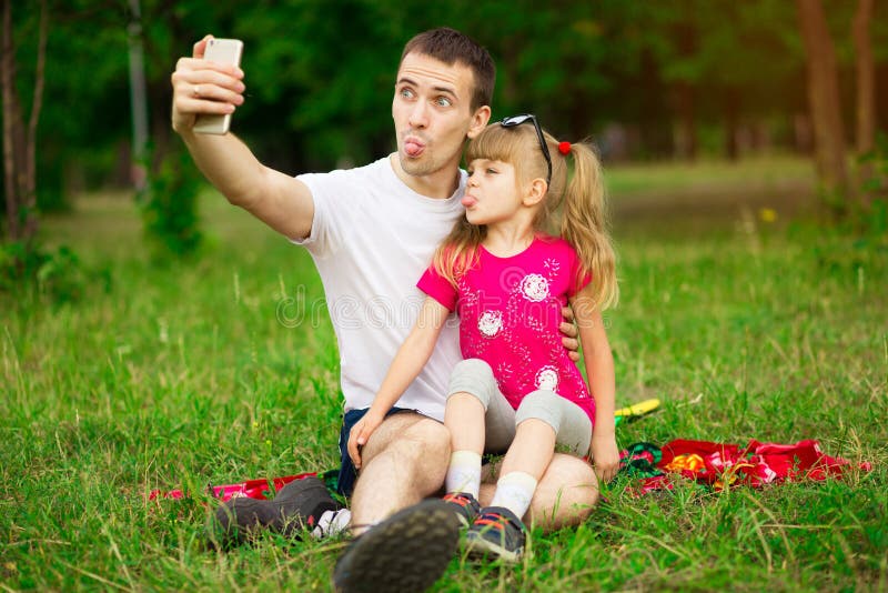 Pai e filha que passam o tempo junto na natureza, tomando selfies e fazendo careta fotos de stock royalty free Pai e filha que passam o tempo junto na natureza, tomando selfies e fazendo careta fotos de stock royalty free