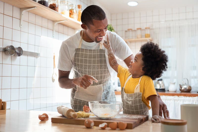 Pai e filho africanos que se divertem em casa durante biscoitos assados
