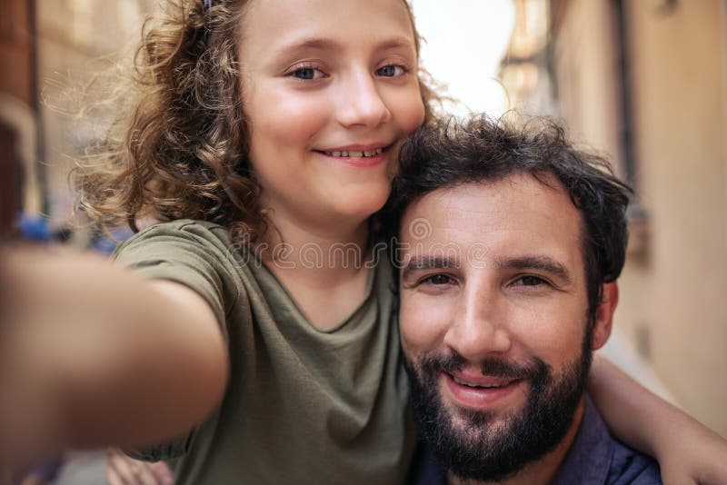 Pai e filho de sorriso que tomam selfies em uma rua da cidade fotos de stock Pai e filho de sorriso que tomam selfies em uma rua da cidade fotos de stock