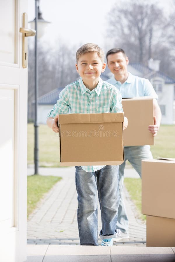 Happy father and son with cardboard boxes entering new home. Happy father and son with cardboard boxes entering new home