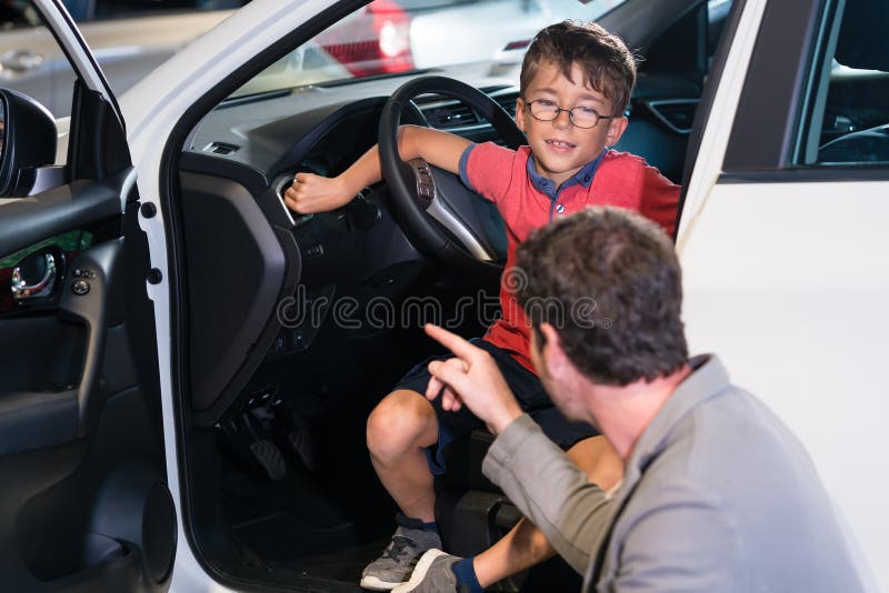 Father and son buying new family car at auto dealership. Father and son buying new family car at auto dealership