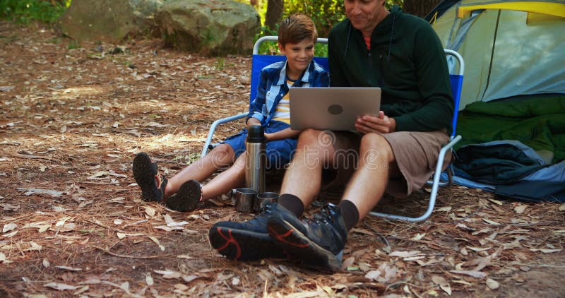 Pai e filho que usa o portátil fora da barraca