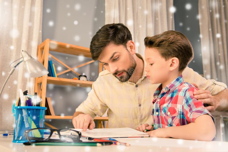 Father and son sitting at the table and reading on new year holidays. Father and son sitting at the table and reading on new year holidays.