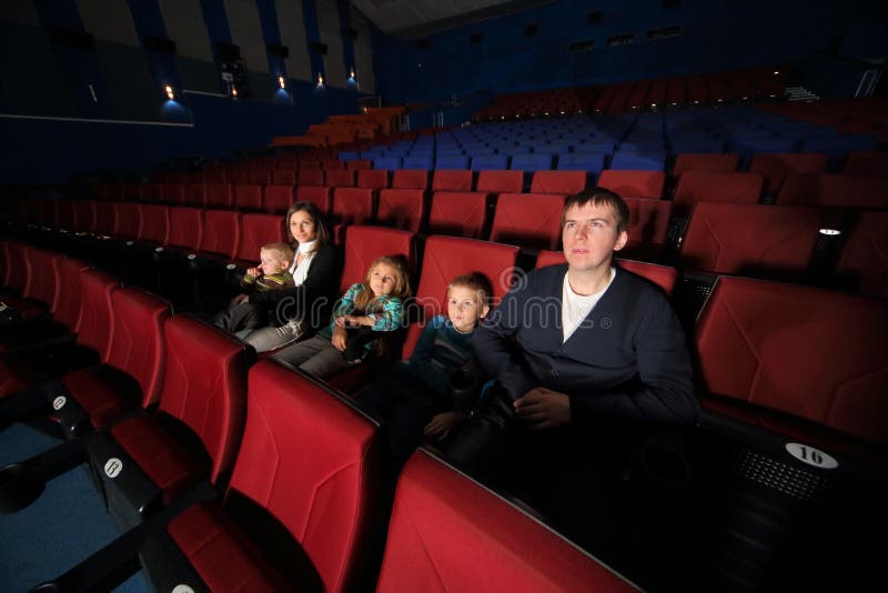 Pai e mãe com as crianças que olham o filme foto de stock Pai e mãe com as crianças que olham o filme foto de stock