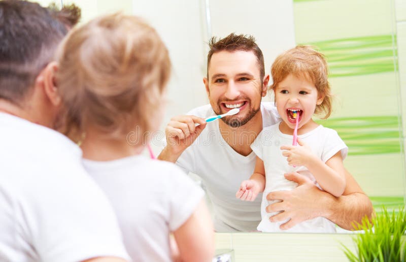 Pai feliz da família e menina da criança que escova seus dentes no bathroo imagem de stock royalty free Pai feliz da família e menina da criança que escova seus dentes no bathroo imagem de stock royalty free