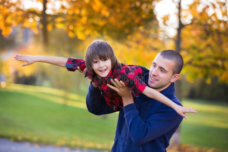 Pai feliz e criança novos que têm o divertimento exterior no parque imagem de stock Pai feliz e criança novos que têm o divertimento exterior no parque imagem de stock