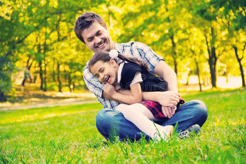 Pai que abraça a filha no parque fotografia de stock royalty free Pai que abraça a filha no parque fotografia de stock royalty free