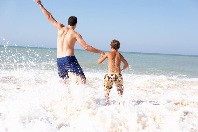 Pai que joga com o menino novo na praia foto de stock Pai que joga com o menino novo na praia foto de stock