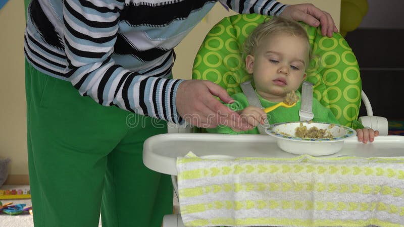 Pai solitário ajudando seu filho pequeno a comer mosto de aveia do prato