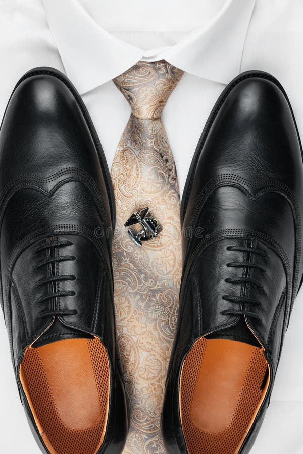 Paia delle scarpe nere classiche che stanno su una camicia e su un legame Modo del ` s degli uomini immagine stock libera da diritti Paia delle scarpe nere classiche che stanno su una camicia e su un legame Modo del ` s degli uomini immagine stock libera da diritti