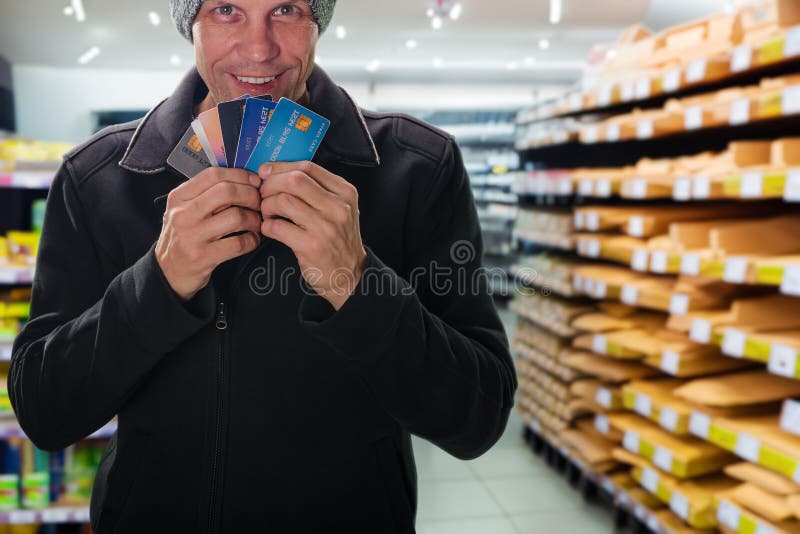 Smiling young man holding credit card in hands for making financial transaction at hardware store. Transaction complete: Payment card used to settle hardware store purchase. Smiling young man holding credit card in hands for making financial transaction at hardware store. Transaction complete: Payment card used to settle hardware store purchase