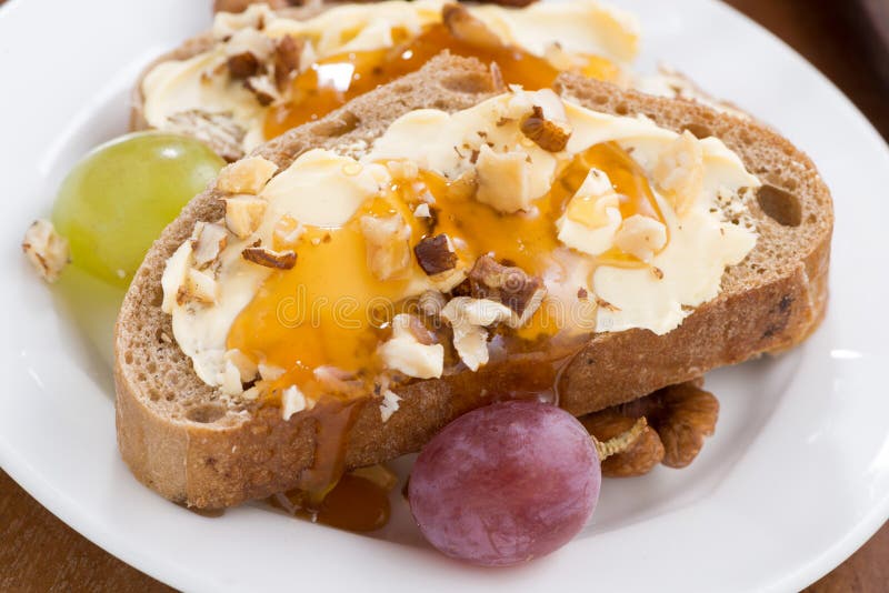 Pain avec du beurre, le miel, des écrous et des raisins photos stock Pain avec du beurre, le miel, des écrous et des raisins photos stock