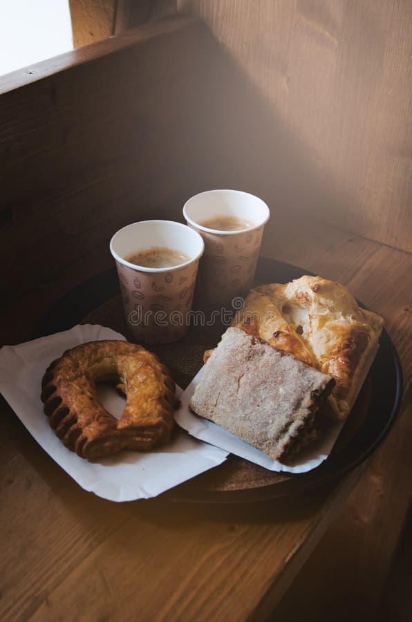Pain doux frais de boulangerie, deux tasses de papier d'emballage de café noir sur un magasin, fond en bois Concept de pause-café image libre de droits Pain doux frais de boulangerie, deux tasses de papier d'emballage de café noir sur un magasin, fond en bois Concept de pause-café image libre de droits