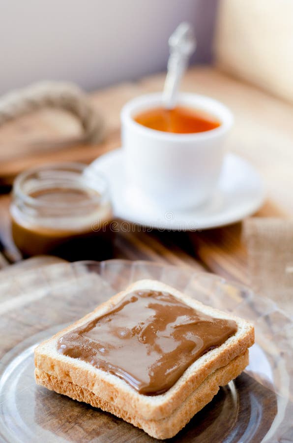 Pain grillé avec le beurre d'arachide et une tasse de thé photo stock Pain grillé avec le beurre d'arachide et une tasse de thé photo stock